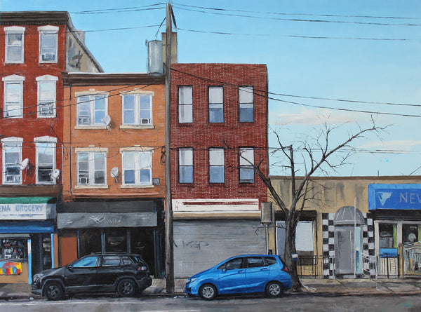 Street scene with brick buildings and cars parked on a street corner.
