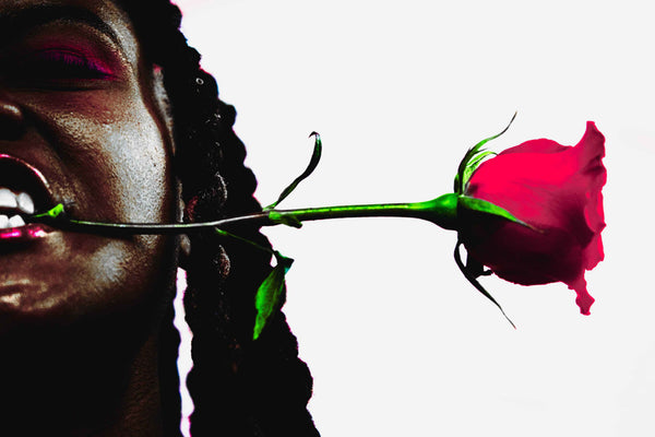 Close-up of a person with a red rose in front of a white background