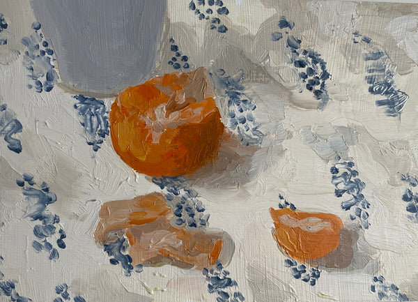 Still life painting with oranges and a cup on a floral-patterned surface