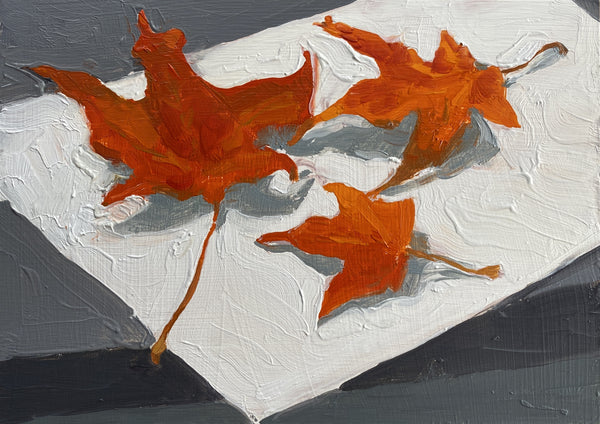 Three orange leaves on a textured gray and white background