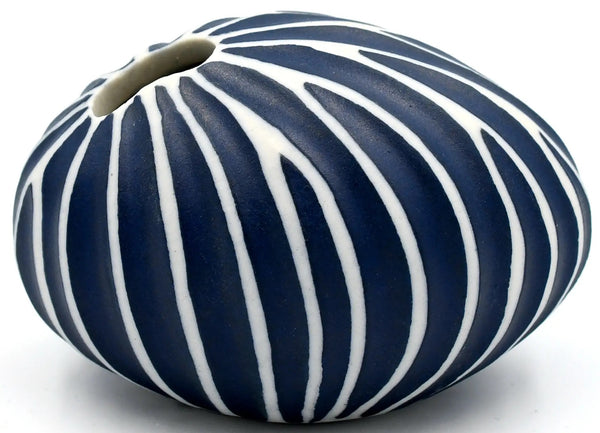 Pebble-shaped porcelain bud vase with ribbed design in navy blue and white stripes, available at Cerulean Arts. 
