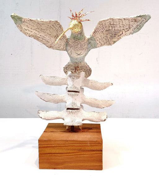 A sculpture titled 'Flight' by Alysa Bennett, featuring an artistic bird made of letters, bones, sticks, and wood.